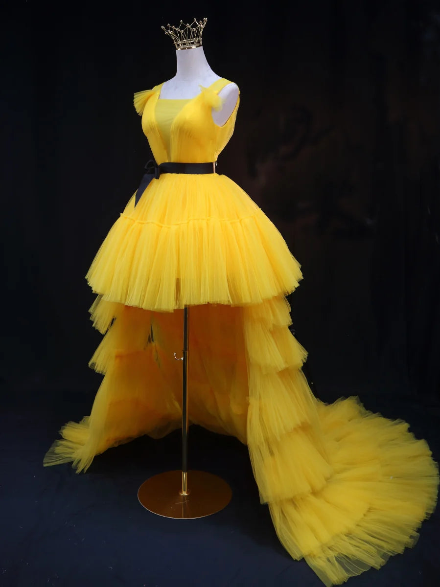 Side profile of a woman in a flowing yellow tulle V-neck formal dress, showcasing the A-line silhouette.