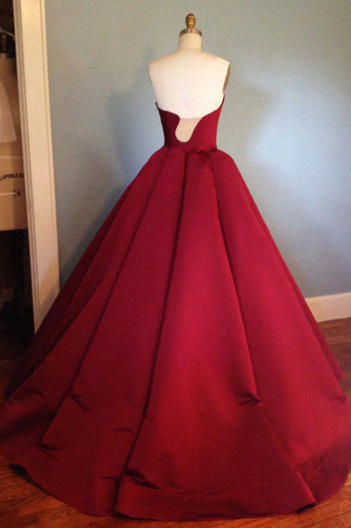 Woman wearing a long burgundy satin evening dress, side view.