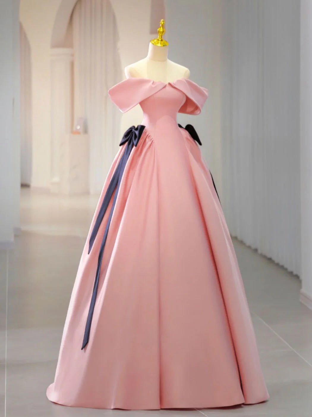 Front view of a woman wearing an elegant pink satin long prom dress with a fitted waist.