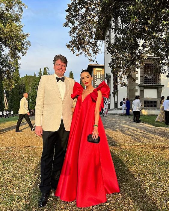 Woman wearing a red satin V-neck floor-length formal evening gown.