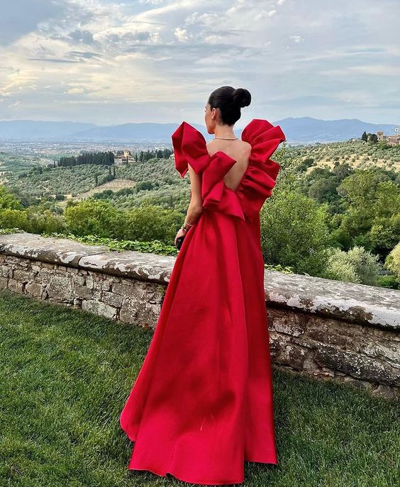 Side view of a woman in a red satin V-neck formal evening gown.