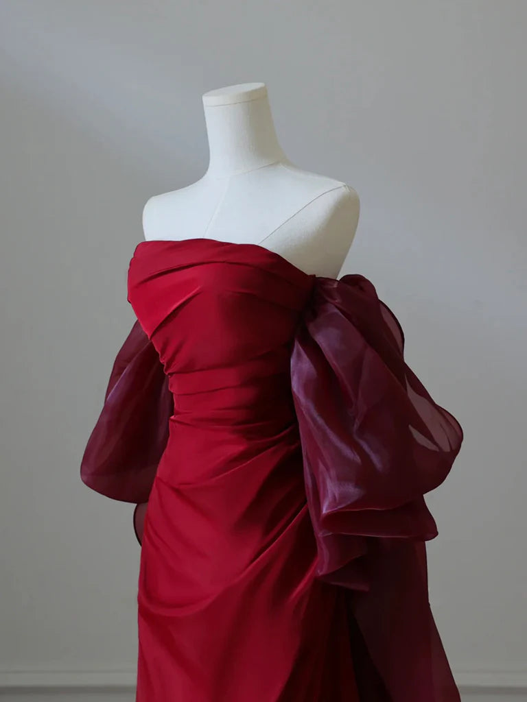 Back view of a model in a flowing burgundy satin evening gown.