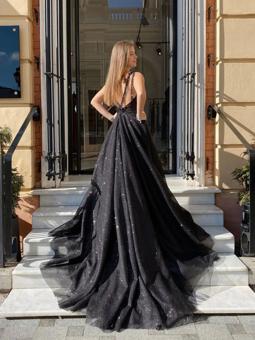 Model posing in a sophisticated black V-neck tulle long evening gown.