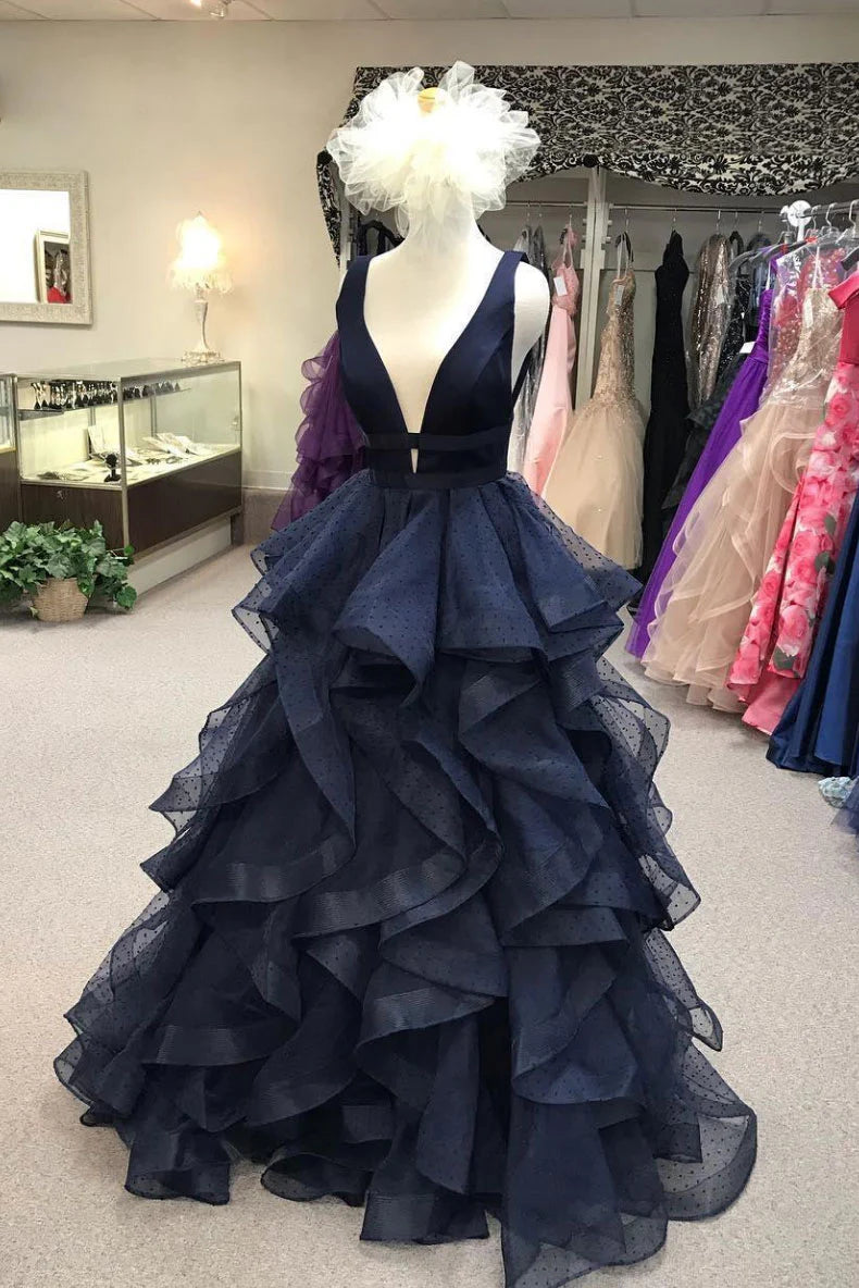 Woman wearing a dark blue tulle long prom dress with a cinched waist.