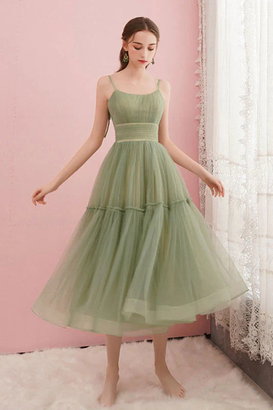 Model wearing a short green V-neck A-line tulle dress, suitable for prom or homecoming.