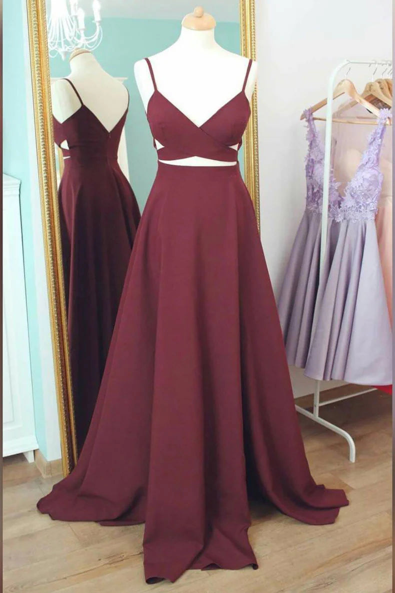 Woman wearing an elegant burgundy V-neck long prom dress with spaghetti straps.