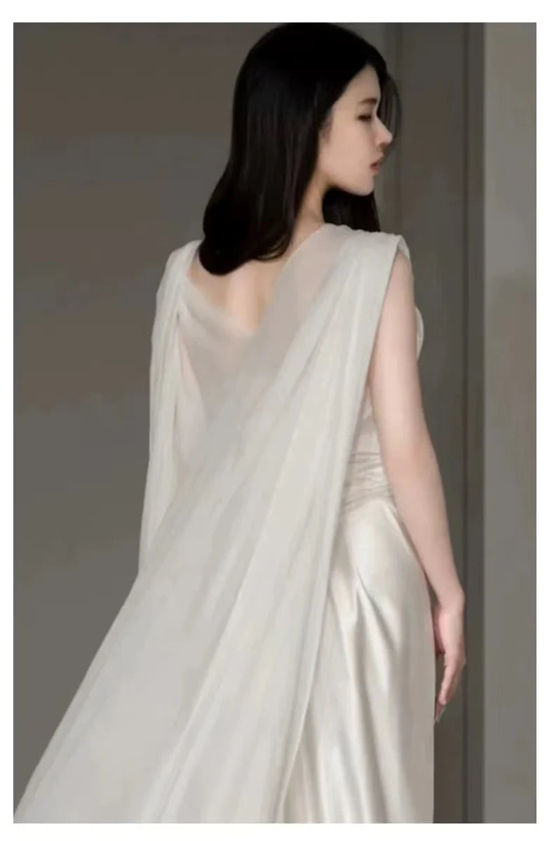 Back view of a white satin wedding dress, showing V-neck straps and elegant pleating.