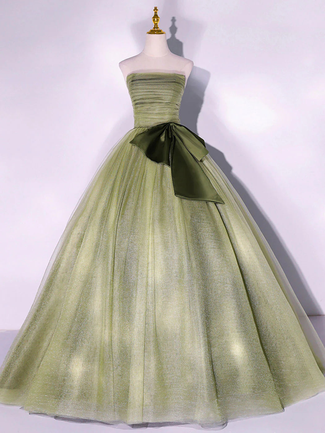 Elegant woman wearing a green A-line tulle long prom dress, front view.
