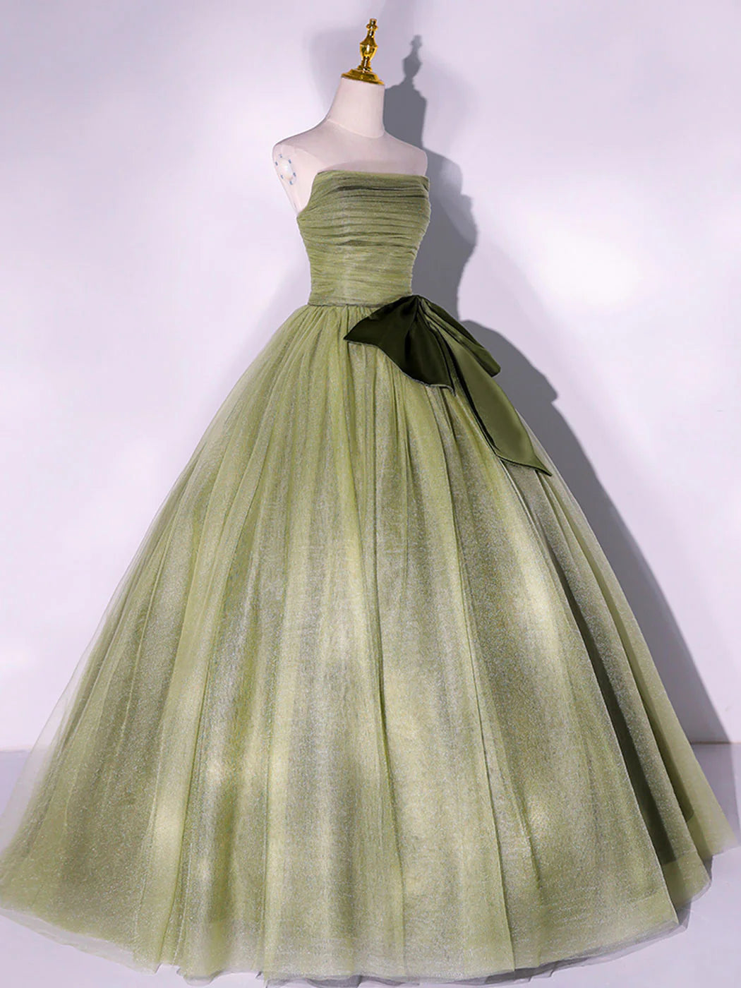 Side profile of a woman in a flowy green A-line tulle evening gown.