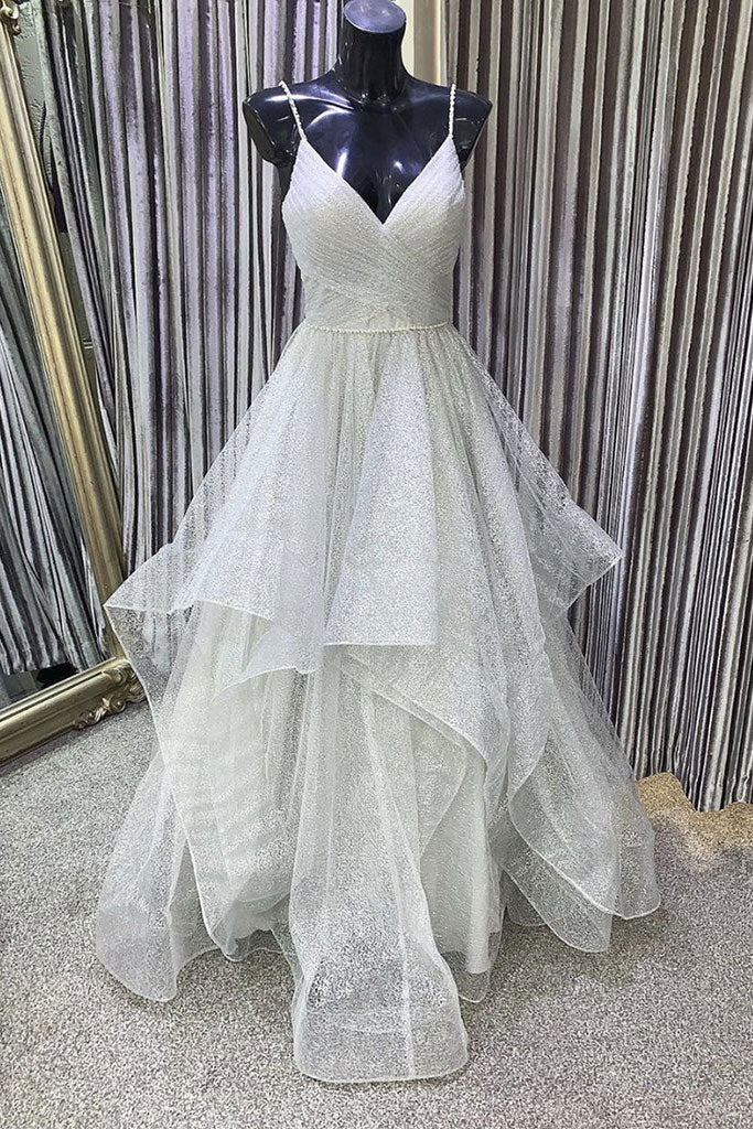 Woman wearing an elegant gray V-neck tulle sequin long prom dress with spaghetti straps.