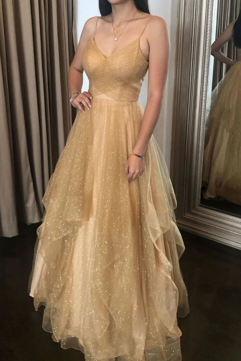 Woman wearing an elegant champagne V-neck tulle long prom dress with spaghetti straps.