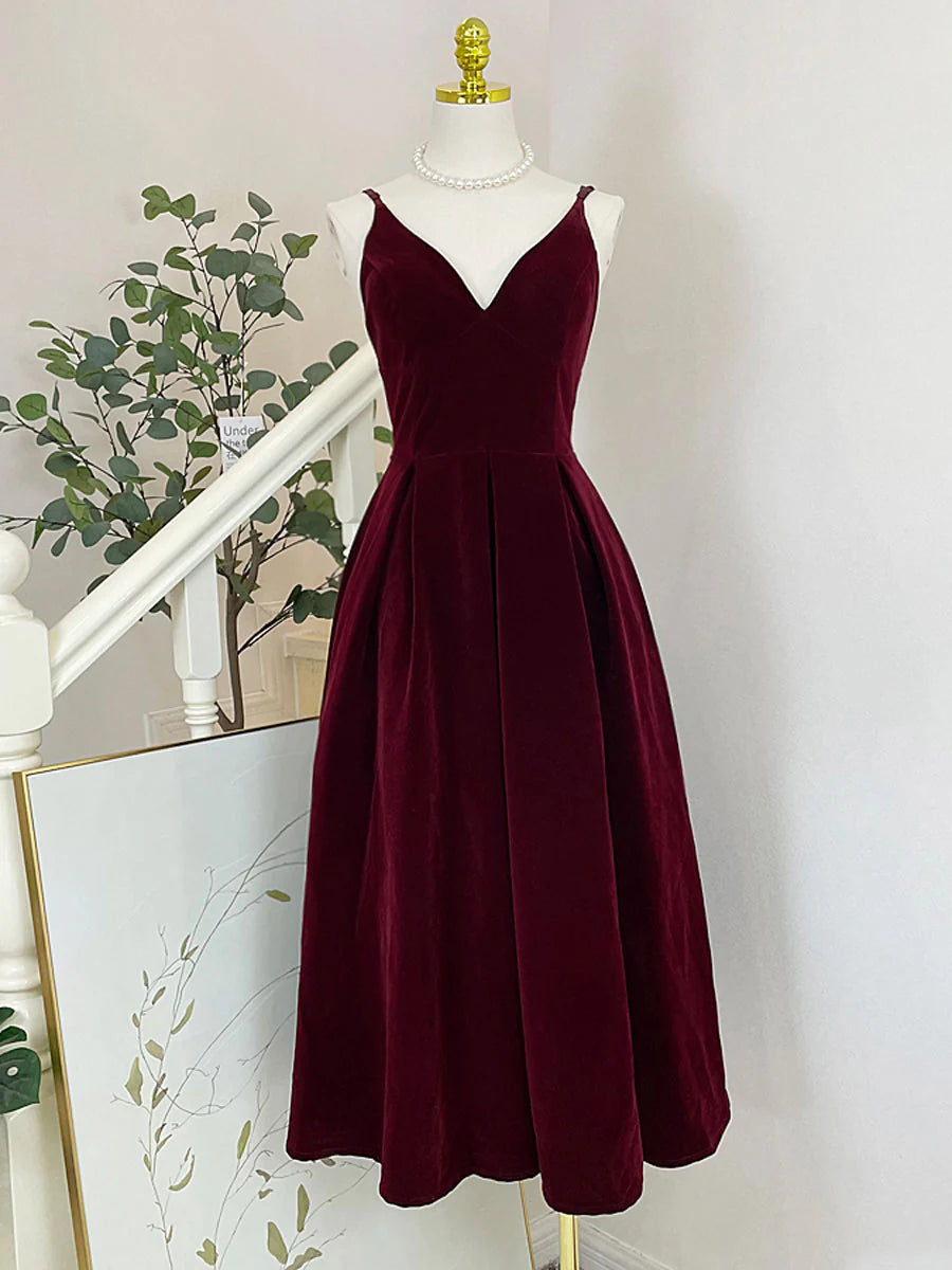 Model in burgundy velvet A-line tea-length prom dress with V-neck and spaghetti straps.