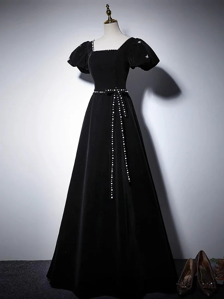 Elegant woman in a black A-line velvet long prom dress, side view.