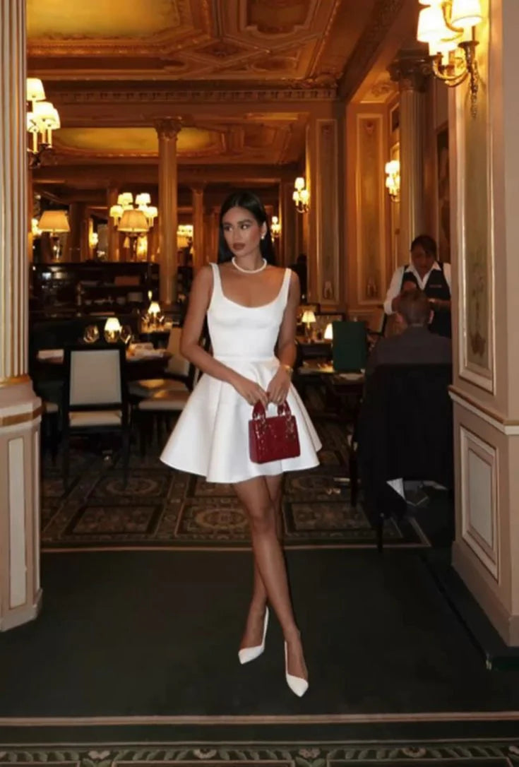 Young woman posing in a white A-line shoulder strap homecoming dress.