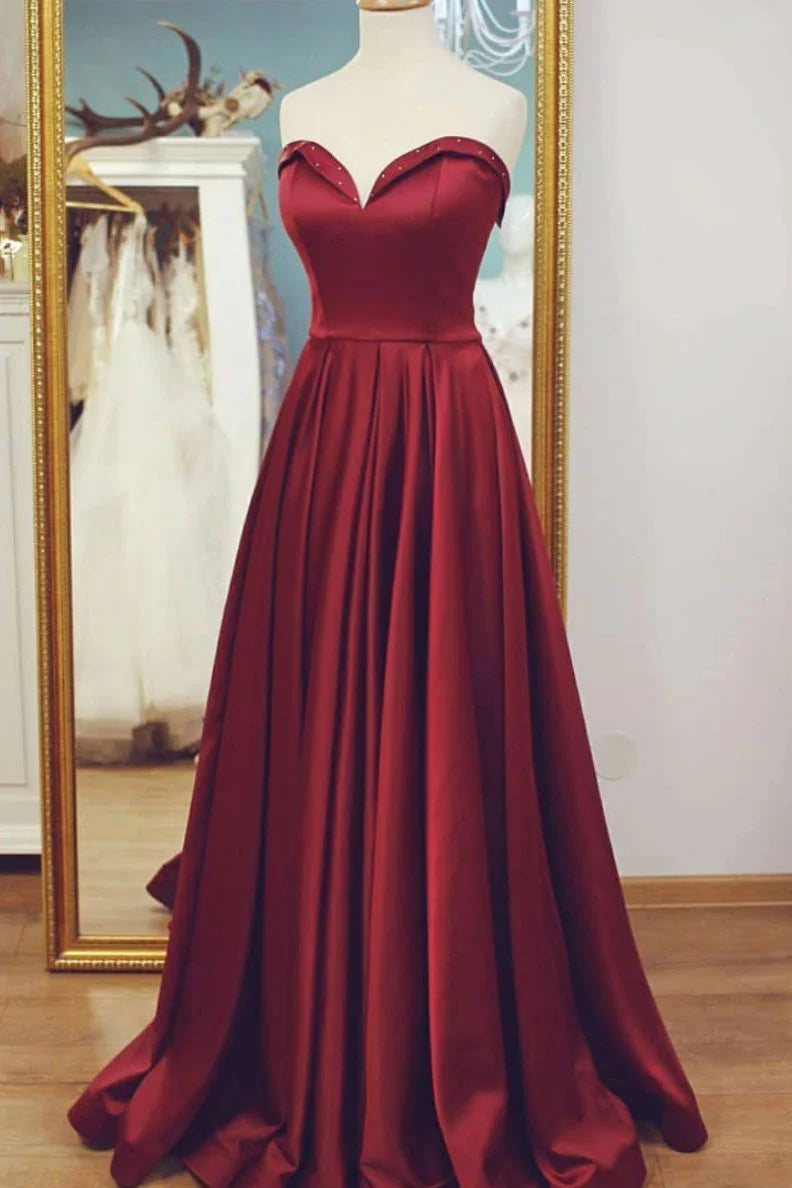 Woman wearing an elegant burgundy satin V-neck floor-length prom dress.