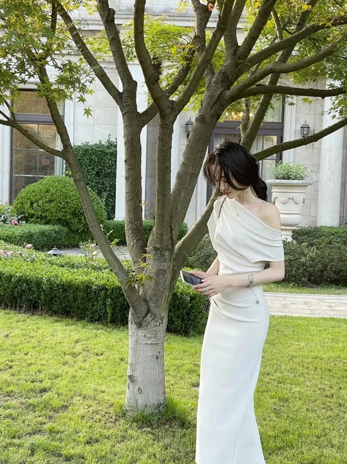 Back view of a woman wearing a black asymmetric pleated V-neck maxi evening dress.