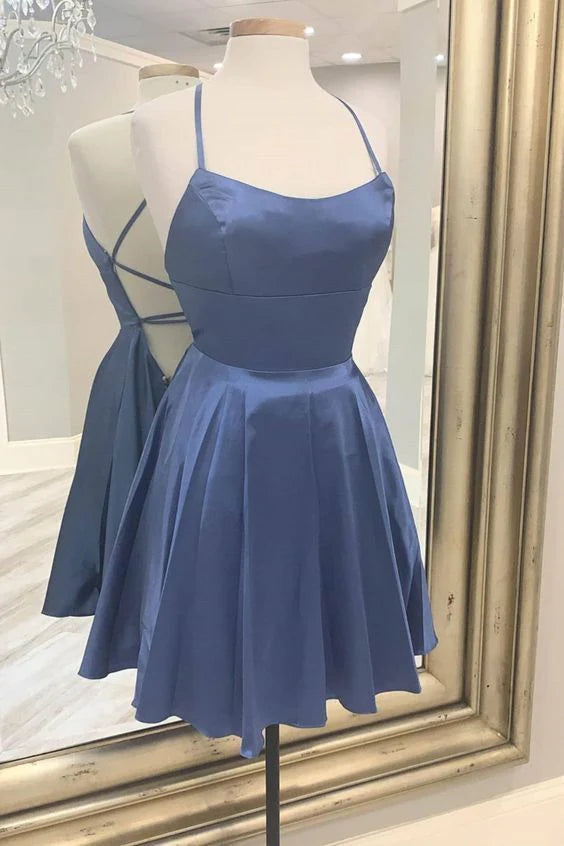 Woman wearing a blue satin backless mini homecoming dress with spaghetti straps.
