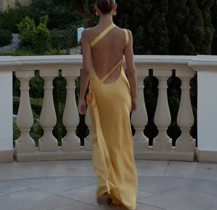 Woman walking in a flowing backless satin maxi dress.