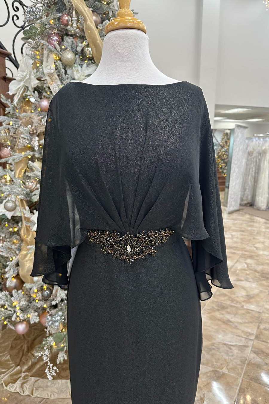 Close-up of the black dress, highlighting rhinestone details on the cape sleeves.