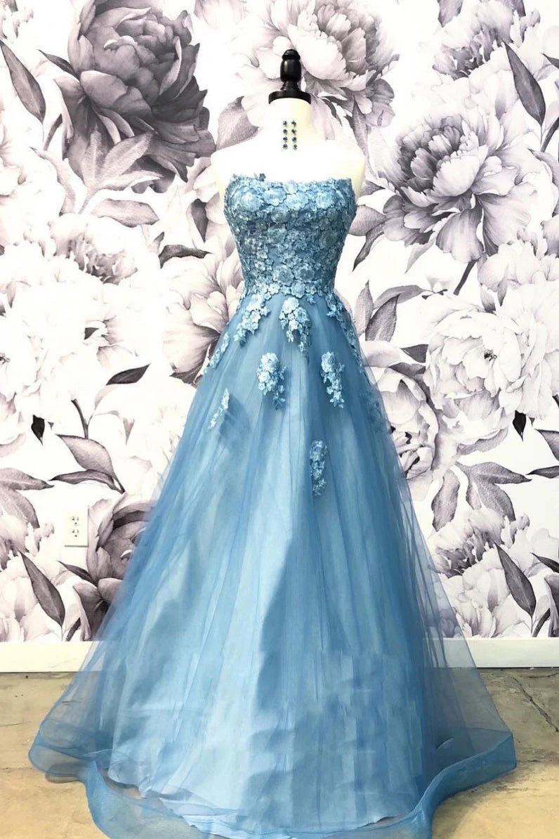 Woman wearing a long blue sweetheart neck tulle applique prom dress.