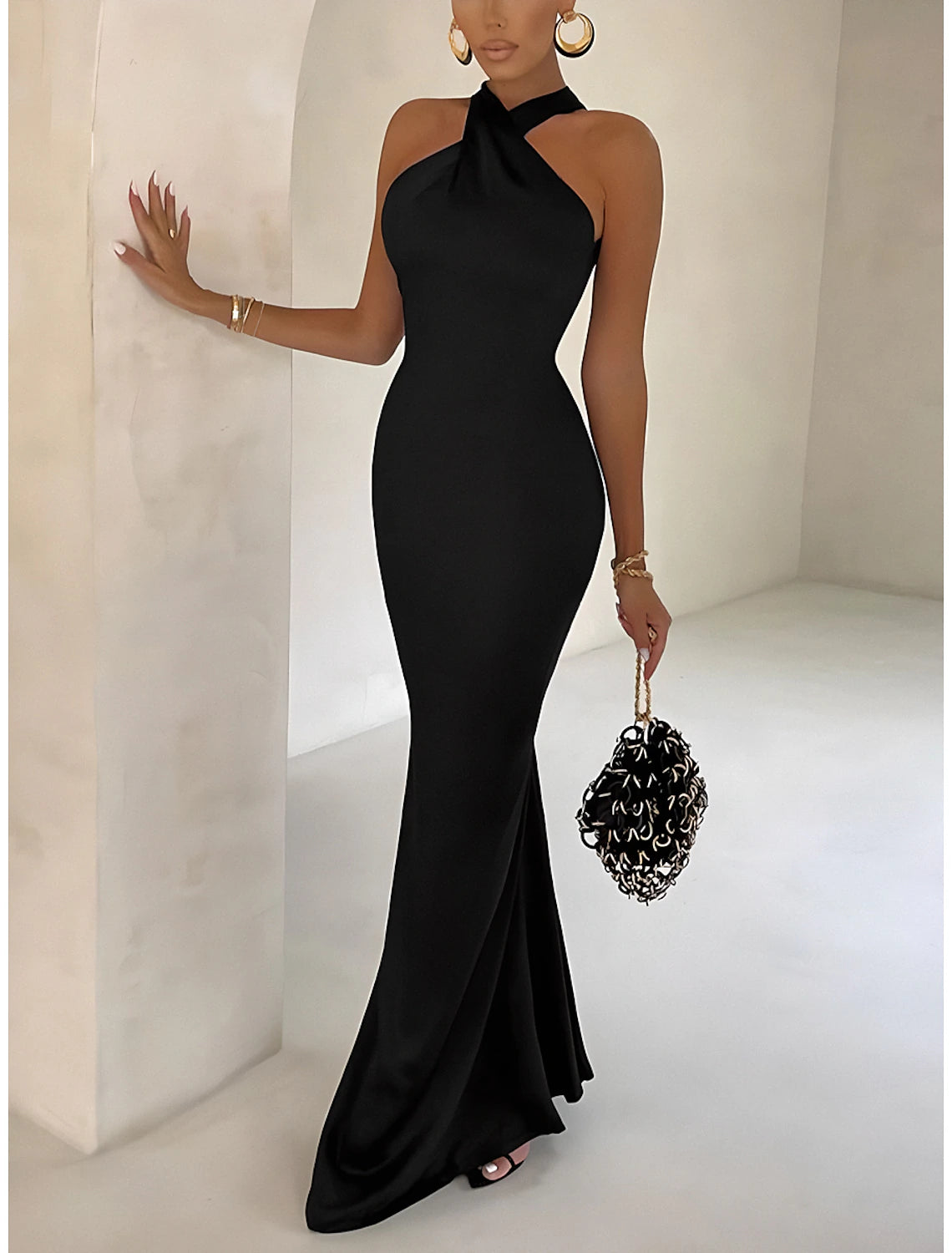 Woman wearing an elegant black bodycon halter neck dress, front view.