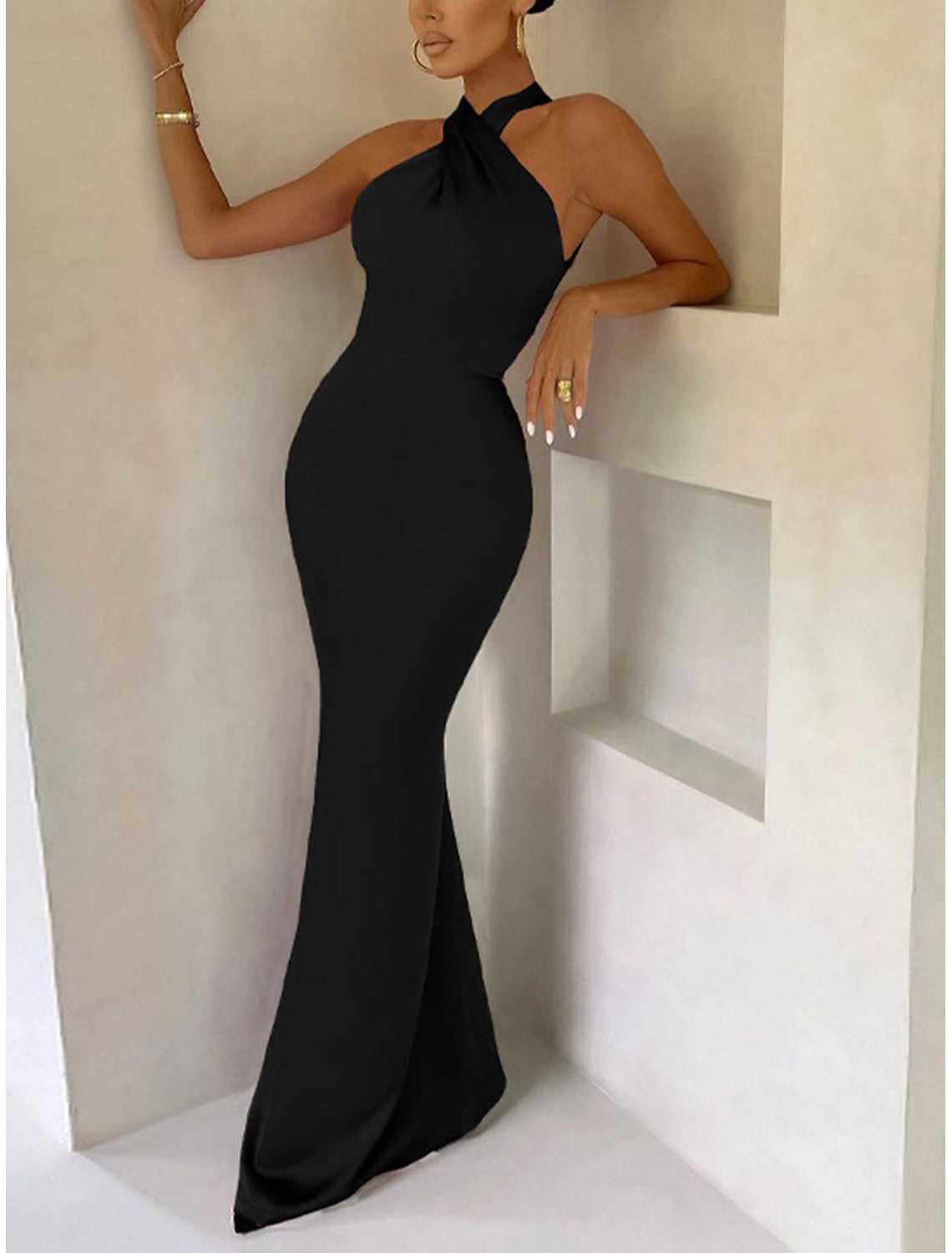 Woman posing in a black backless bodycon party dress, side view.