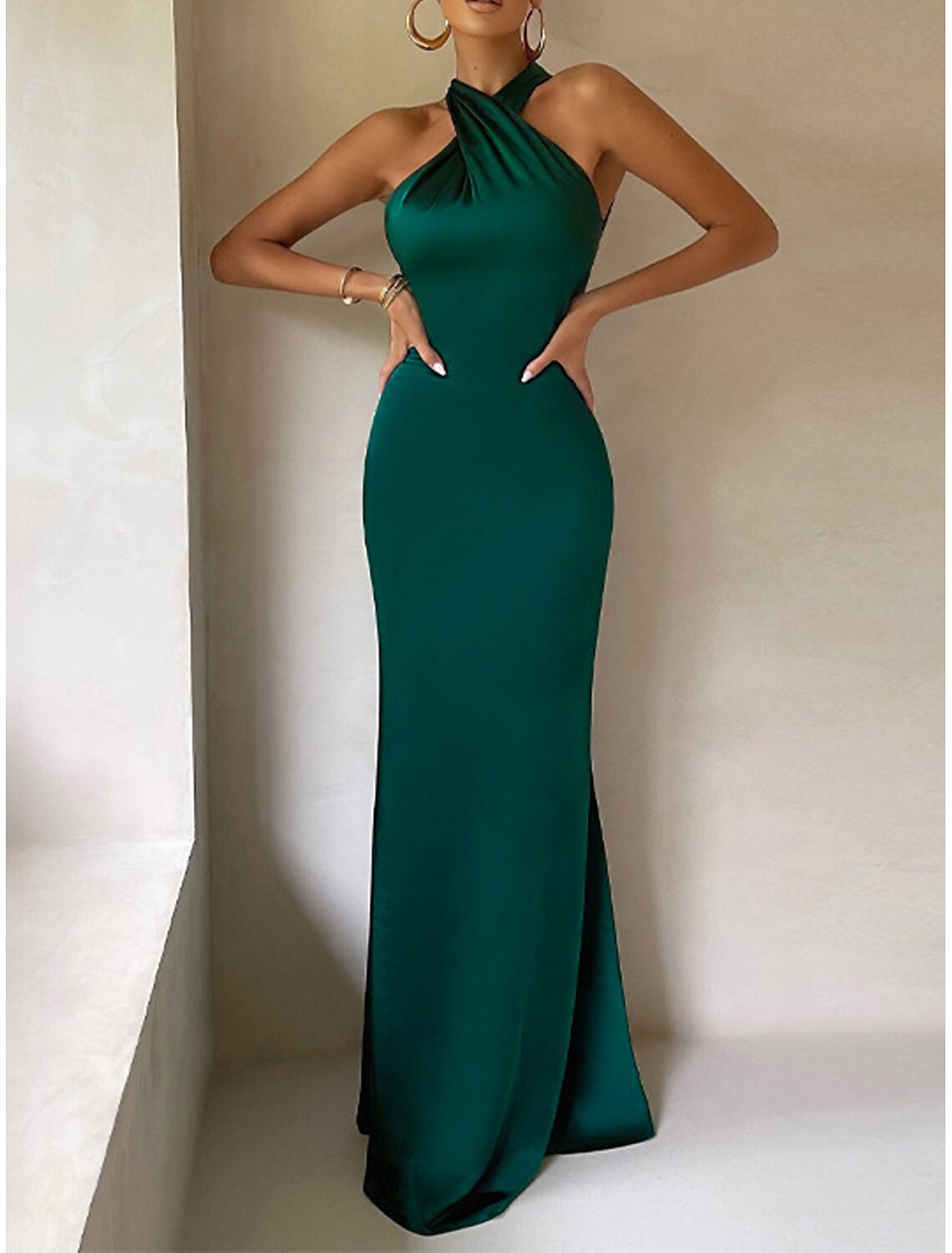 Woman showcasing the backless design of a black formal halter dress.
