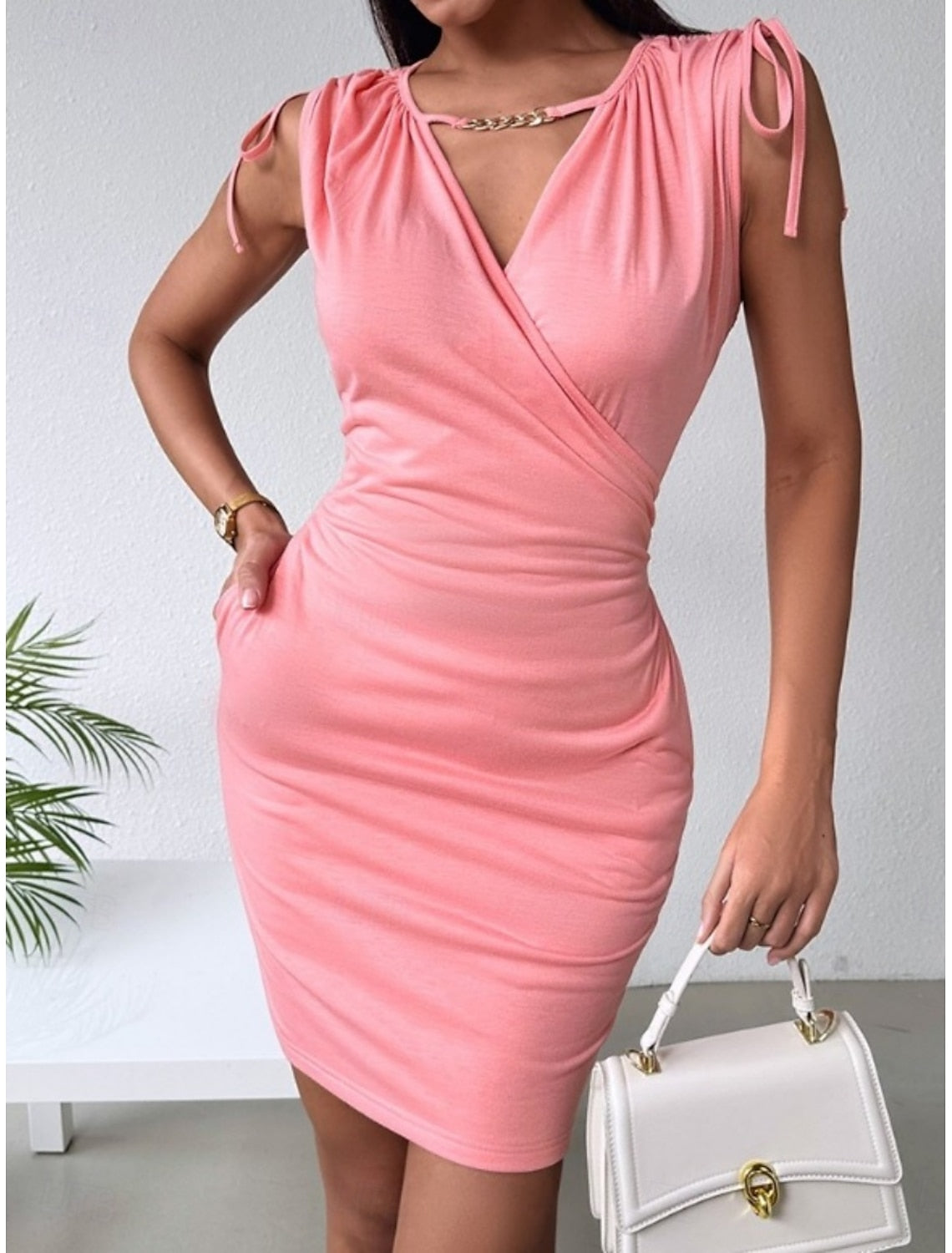 Woman posing in a black off-shoulder V-neck bodycon dress.