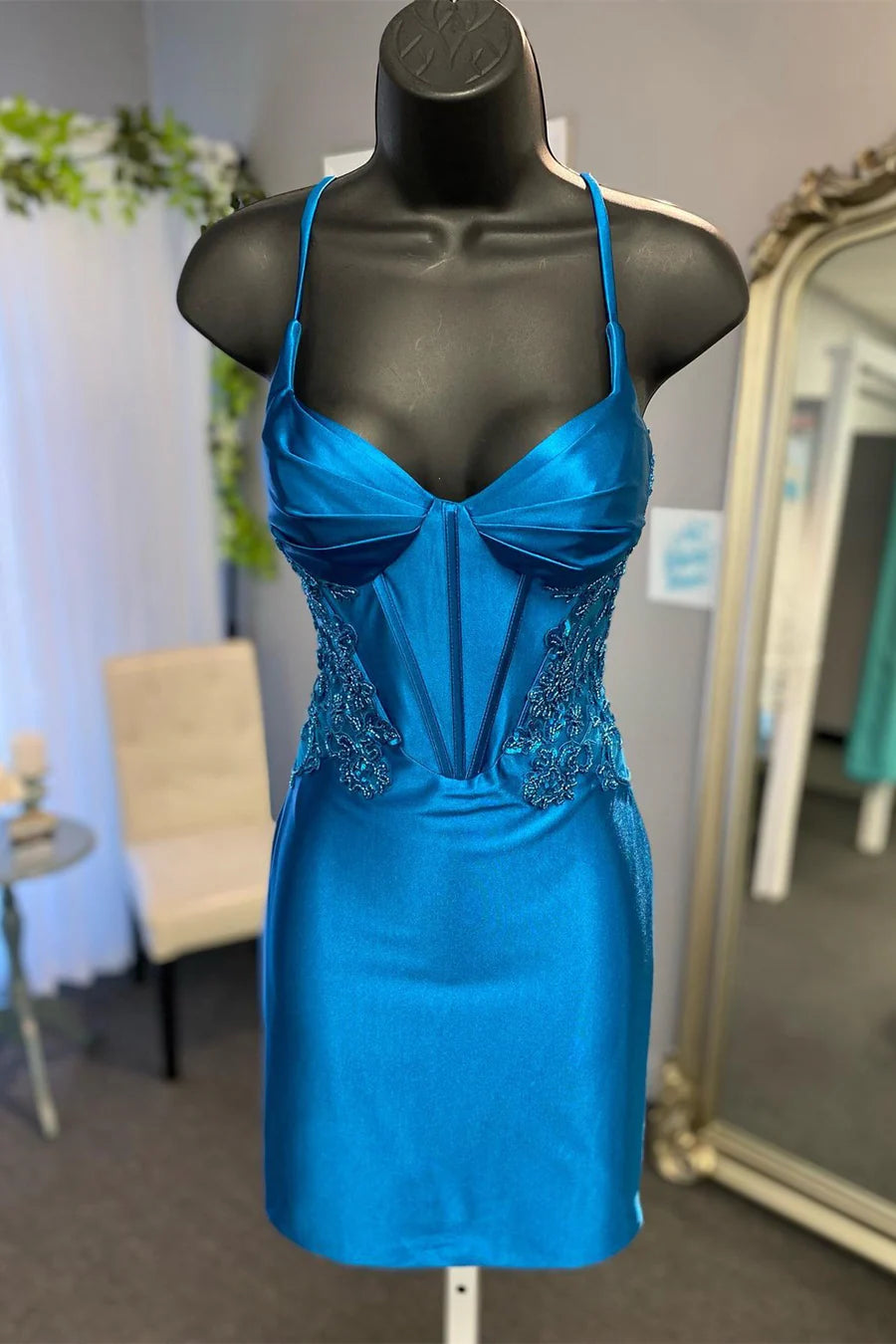 Woman wearing a peacock blue bustier bodycon short dress with intricate appliques.