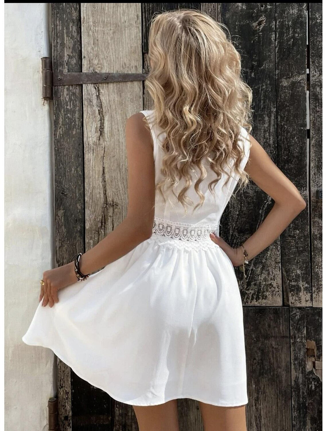 Side view of a woman in a white V-neck sleeveless mini dress.