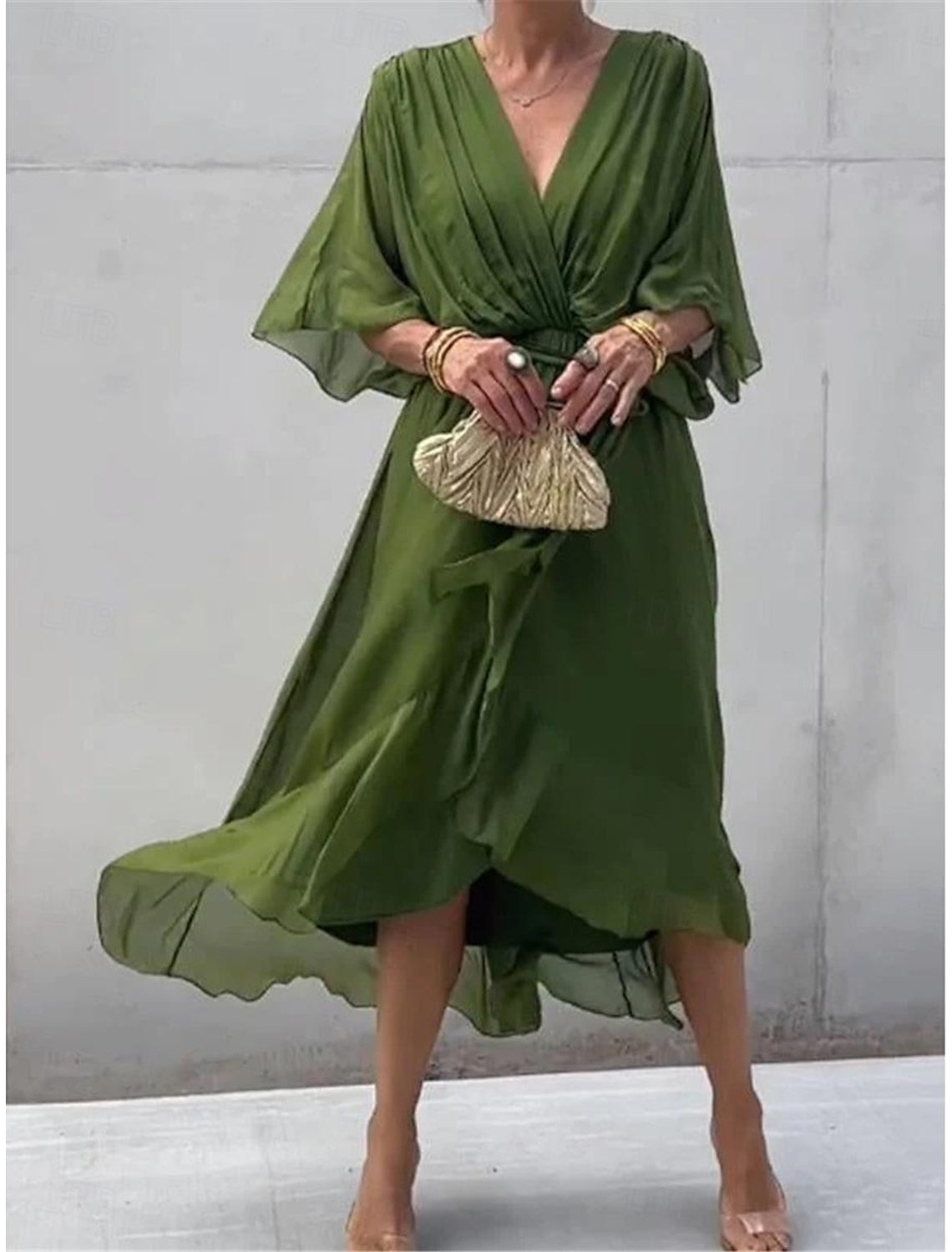 Full view of a woman in a white chiffon V-neck maxi dress with ruffles and 3/4 length sleeves.