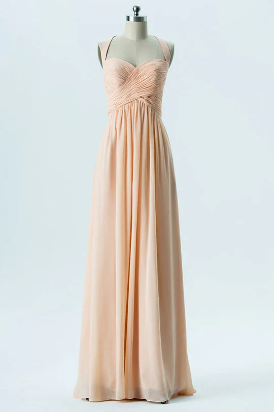Front view of a woman wearing a light orange chiffon sweetheart halter neck bridesmaid dress.