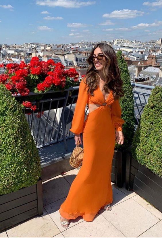 Woman in an elegant orange long sleeve evening dress with a flattering waist.