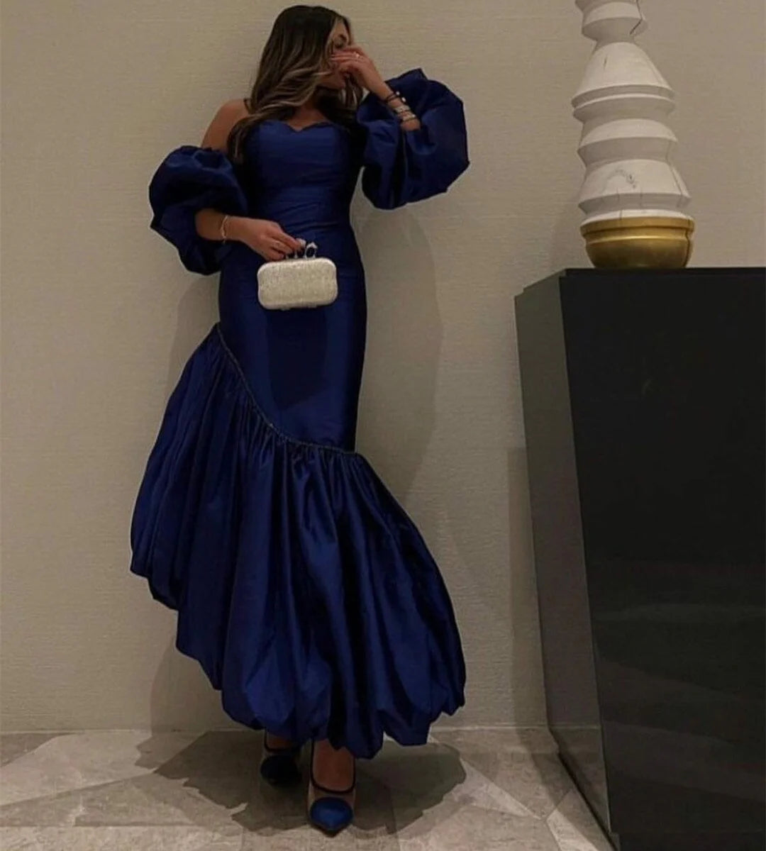 Back view of a woman in a blue off-shoulder satin evening gown.