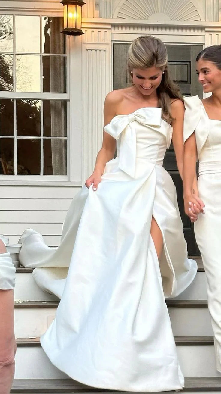 Woman wearing an elegant white strapless wedding dress with a high leg slit.