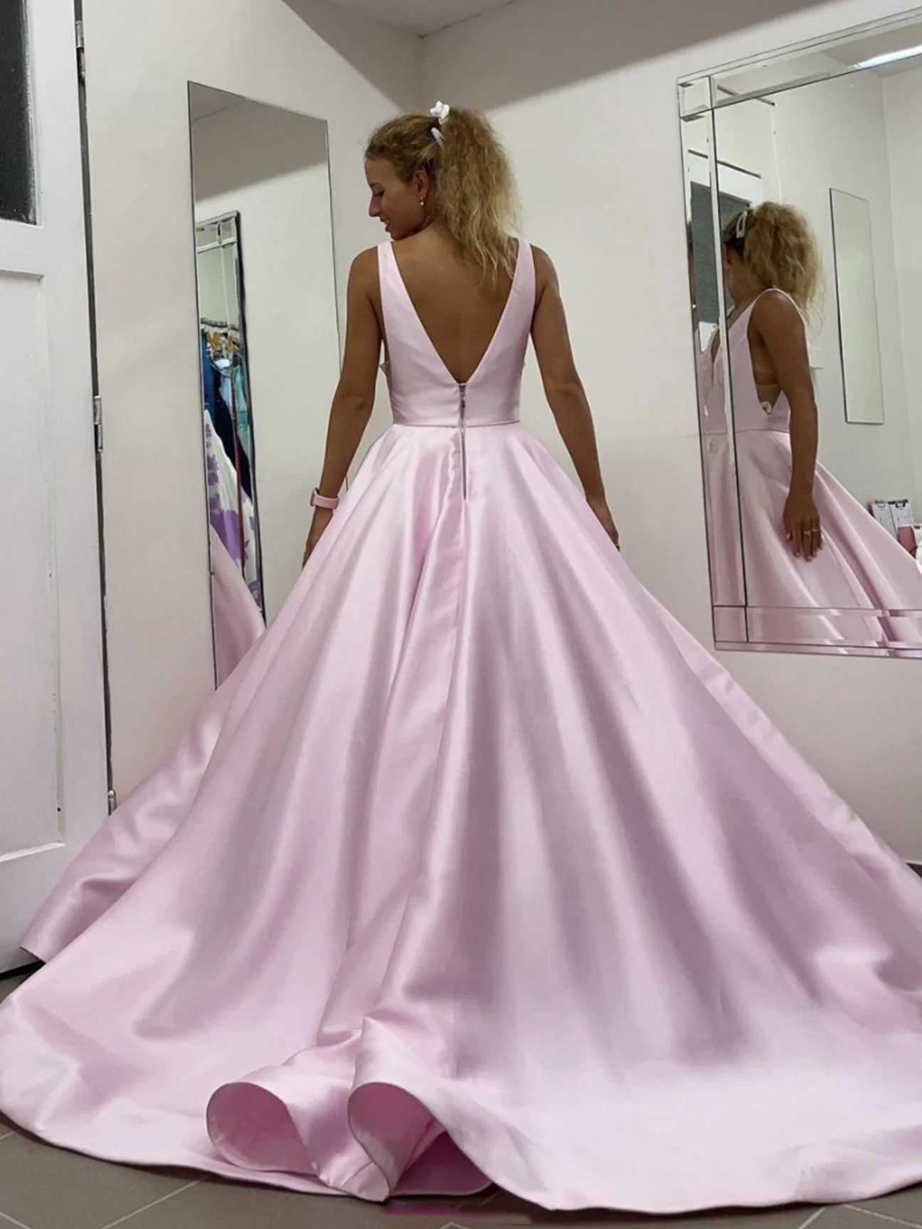 Back view of a woman wearing a pink V-neck satin lace long prom dress.