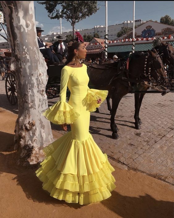 Side view of a woman in a red tiered long sleeve evening gown with Spanish ruffles.