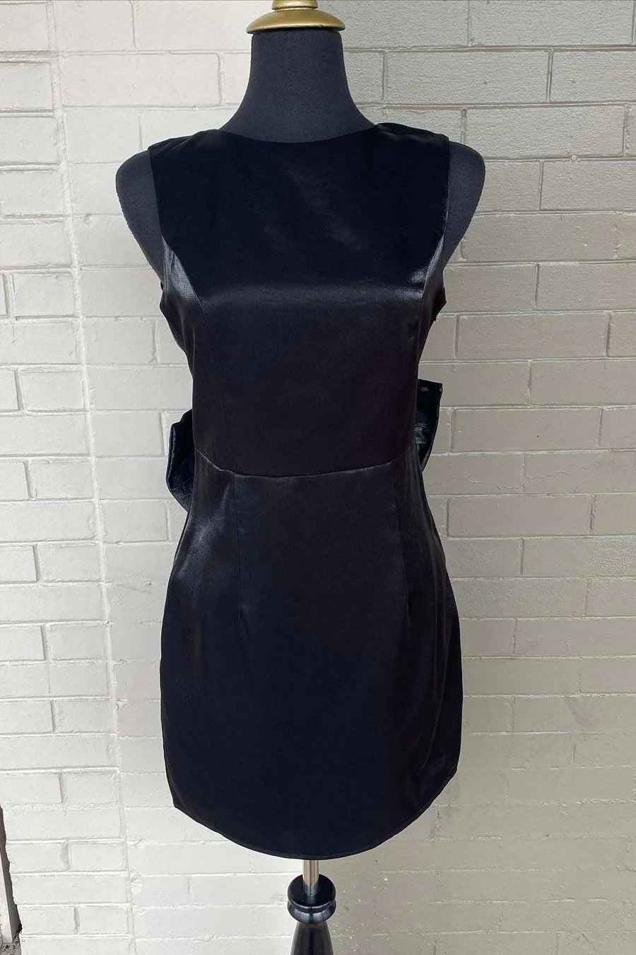 Back view of the sleeveless party dress, showcasing the decorative bow detail.