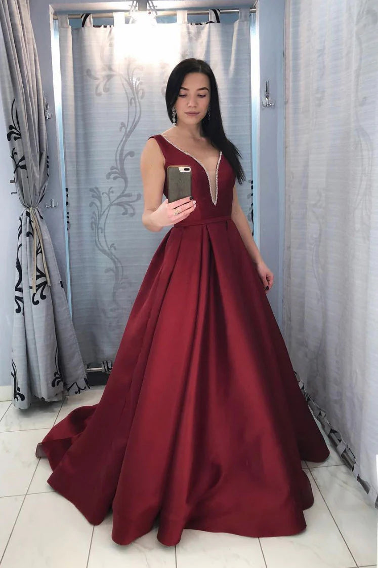 Woman wearing a burgundy V-neck satin long prom dress with a fitted waist.