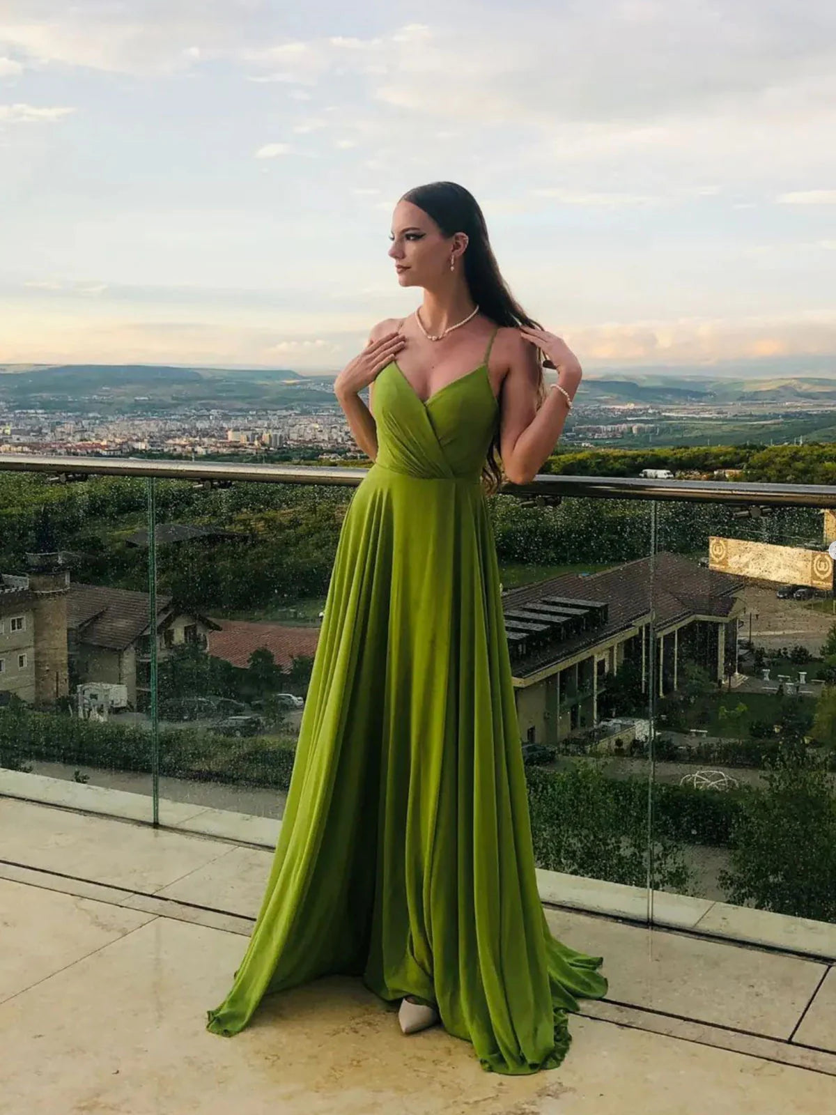 Model posing in an elegant green A-line chiffon long prom dress.
