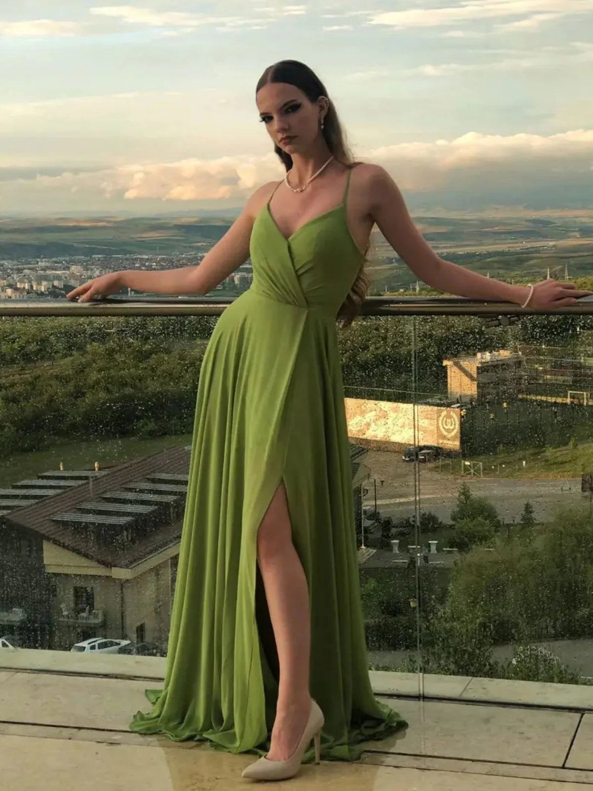 Full-length view of a model wearing a flowing green A-line evening gown.