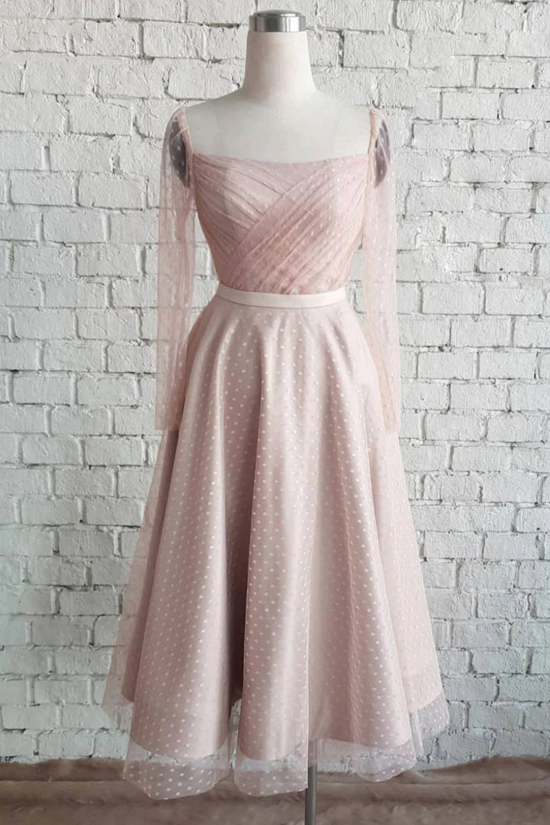 Woman wearing a light pink pleated tulle A-line prom or bridesmaid dress.