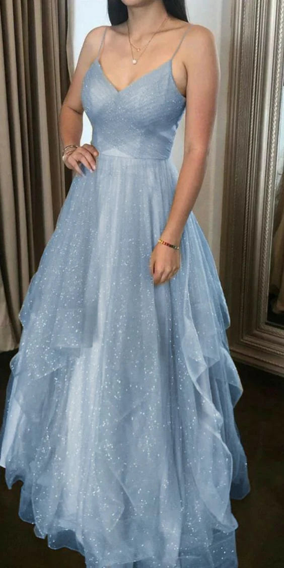 Woman wearing an elegant light blue tulle and chiffon V-neck spaghetti strap long prom dress.