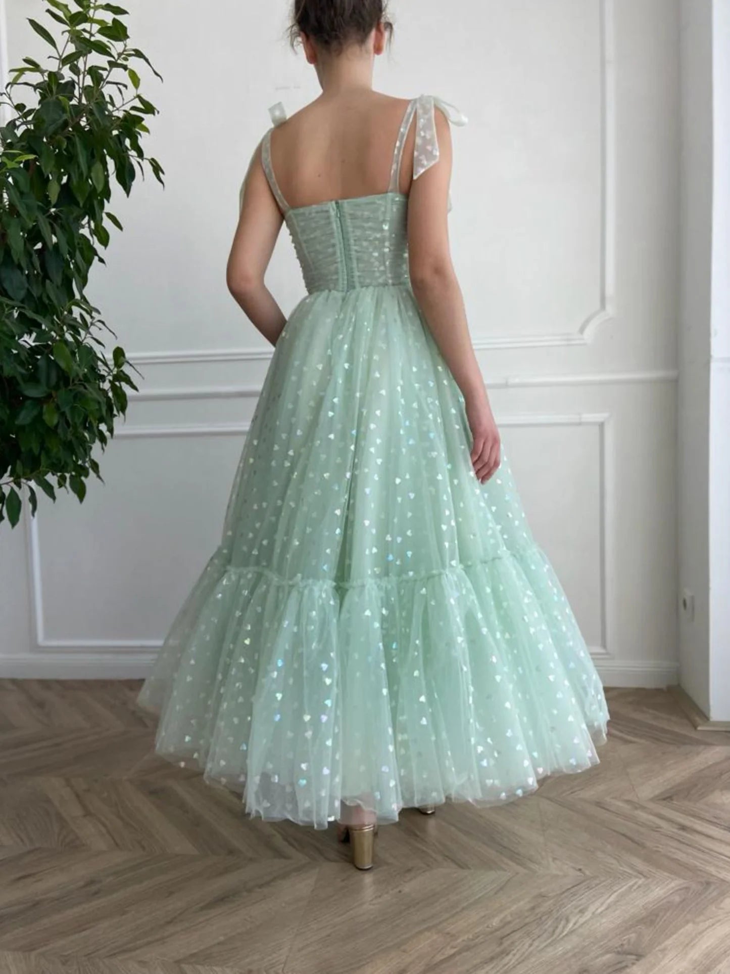 Back view of the green tulle tea length dress, showing its flowy A-line skirt.