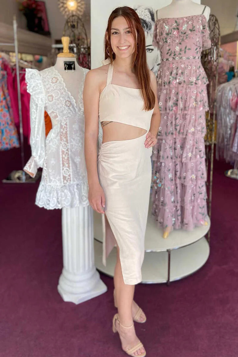 Woman wearing an elegant cream halter cutout wrap midi dress with a side slit.