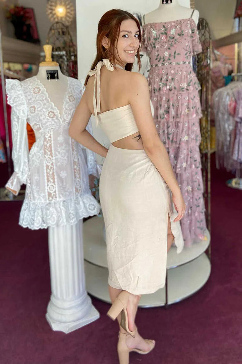 Back view of a woman in a cream halter wrap midi dress with a cutout detail.