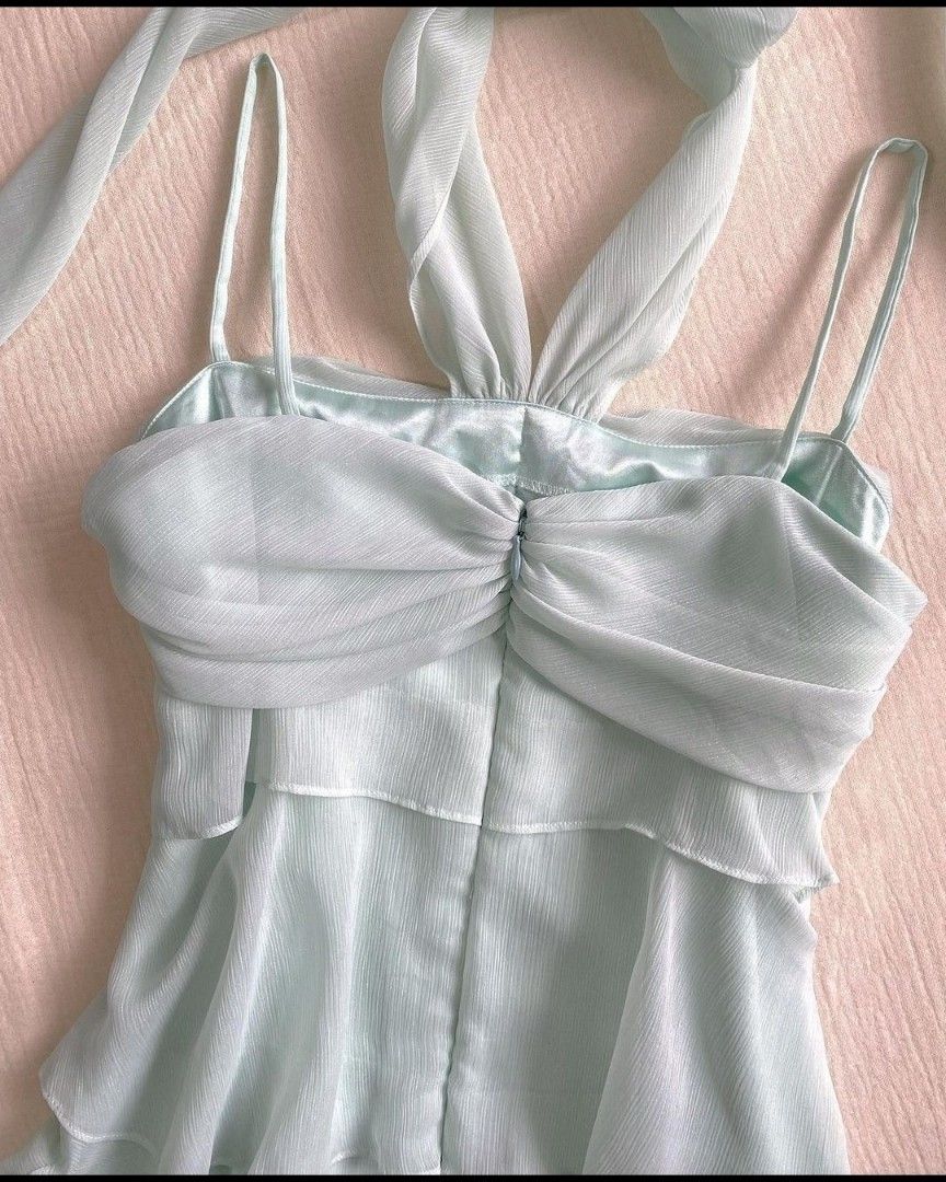 Back view of a model in a short tiered ruched chiffon halter neck dress.