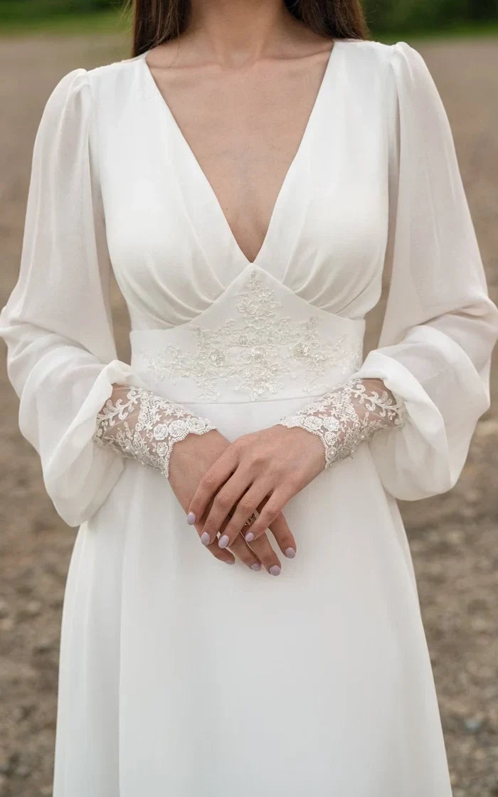 Elegant ivory lace and chiffon wedding dress with long sleeves and a flowing train.