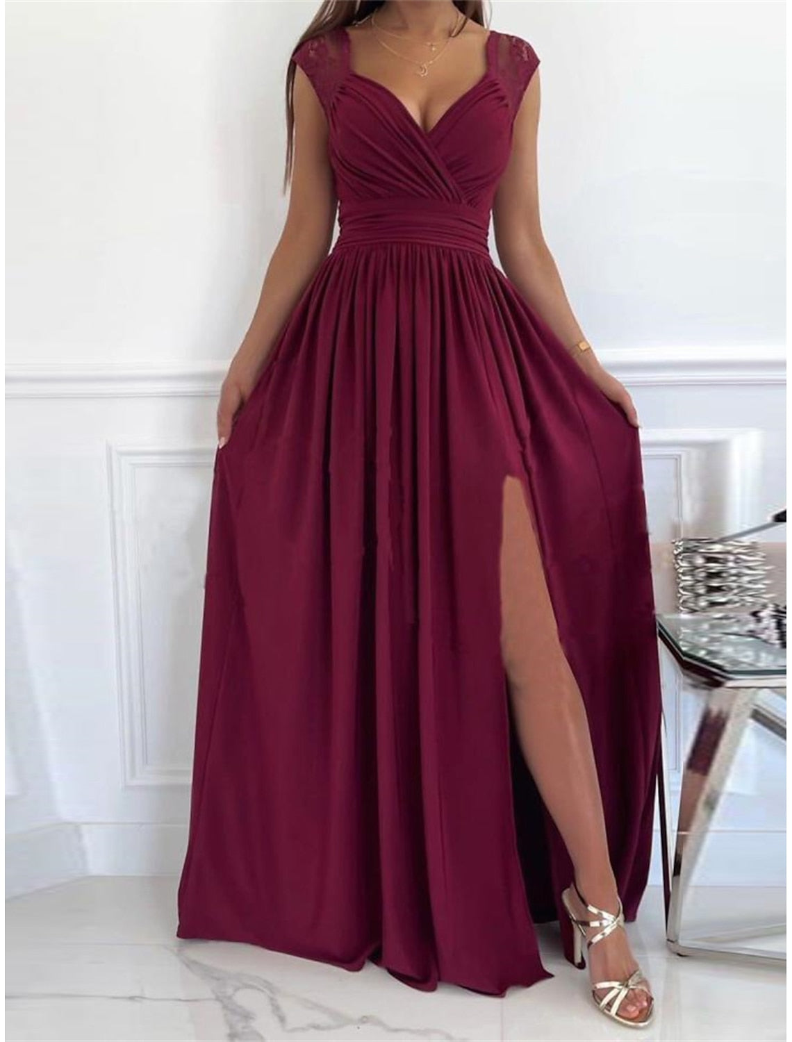 Woman wearing an elegant lace ruched V-neck sleeveless prom dress.