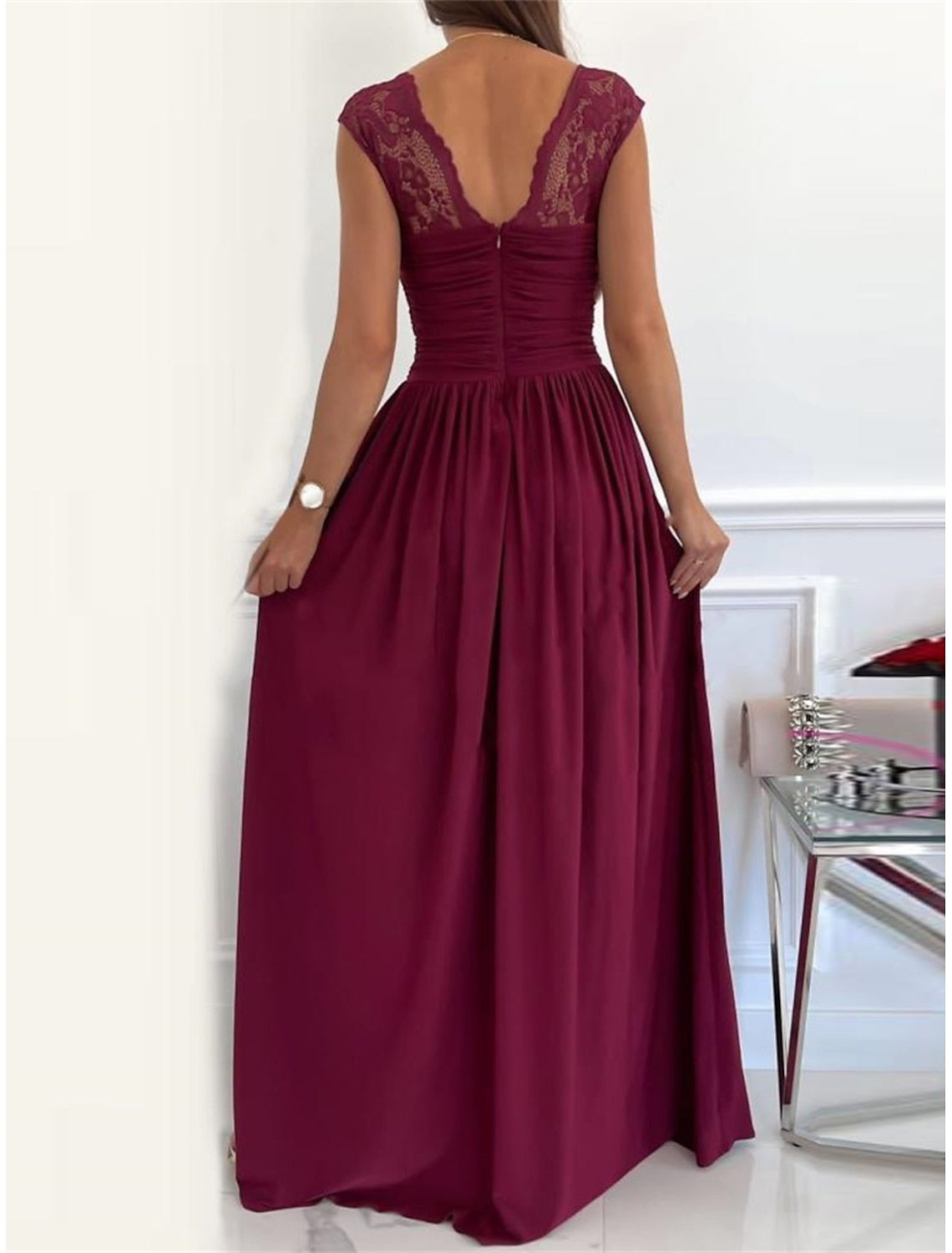 Back view of a woman in a lace ruched V-neck prom dress.
